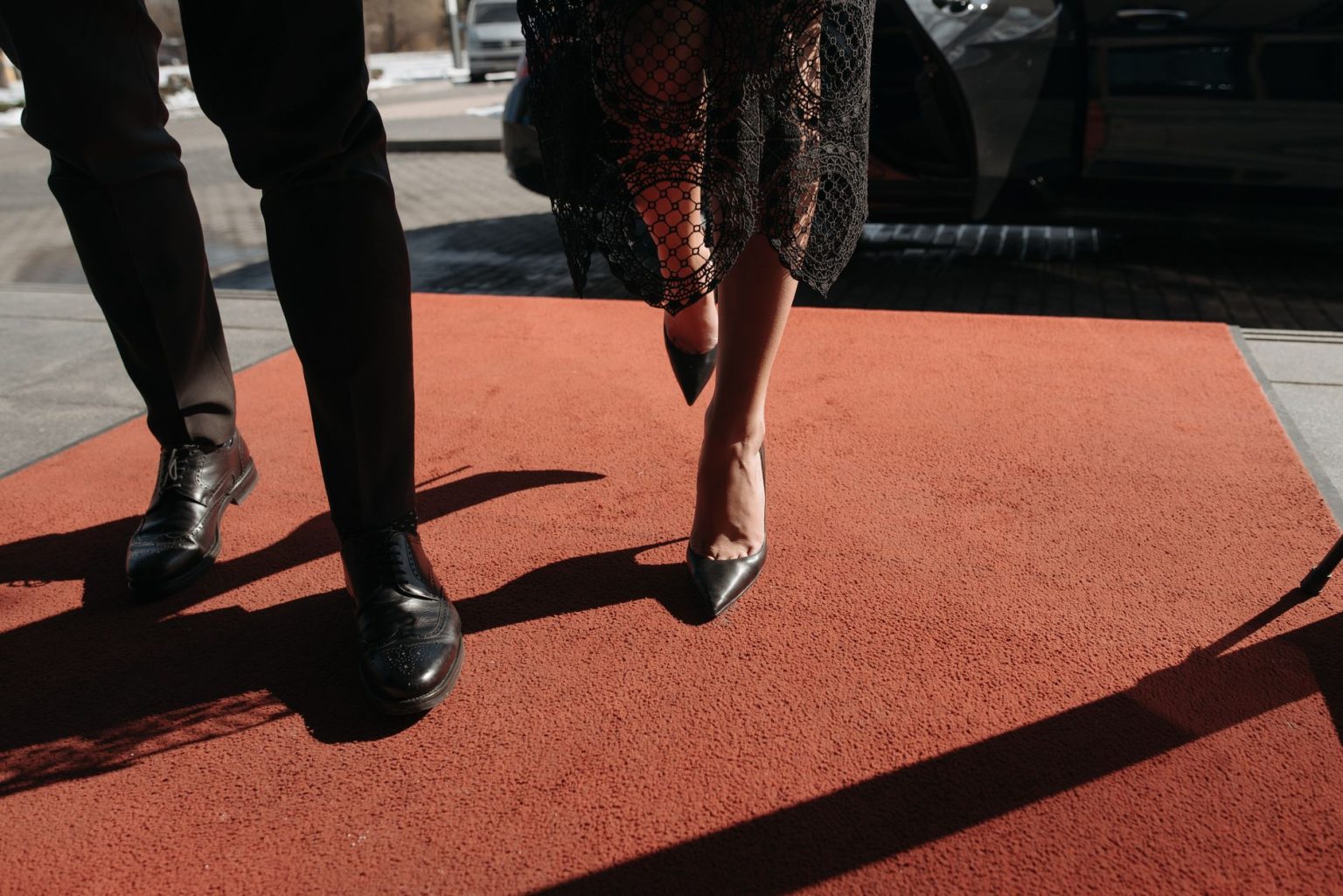 Casal elegantemente vestido posa em um tapete vermelho durante um evento.