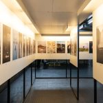Galeria moderna iluminada com fotografias expostas em painéis nas paredes.